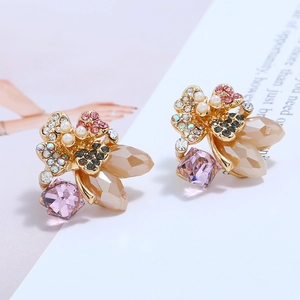 Detailed macro of vintage floral earrings featuring pink rhinestones and elegant pearls