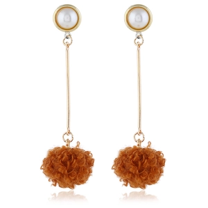Detail of long drop earrings featuring a gold bar with white pearl and brown pom-poms