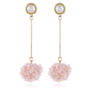 Close-up of long drop earrings with white pearl studs, gold bar, and pink fuzzy pom-poms