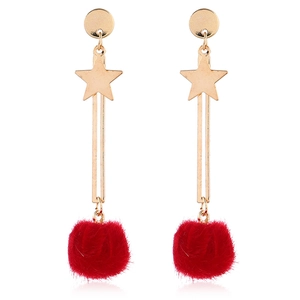 Detail of star-shaped earrings with vibrant red faux fur balls and golden metal drop bars