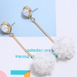 Detailed view of long earrings with white mink fur pompoms and pearl accents