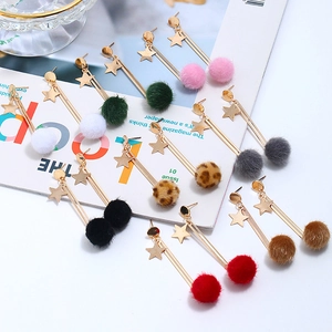 Flat lay of star-shaped earrings with colorful faux fur pom-poms on a fashion magazine