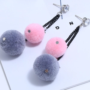 Close-up of plush mink fur pom-poms on long chain earrings with sparkling rhinestone studs
