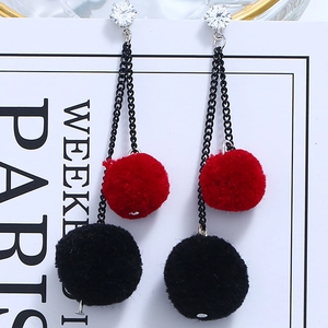 Detailed macro view of red and black fluffy pompom tassels with zircon studs on earrings