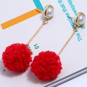 Detailed view of red pompom and pearl earrings with long gold chain for women