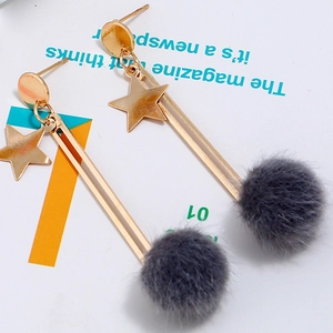Detail of star-shaped earrings with soft faux fur pom-poms and gold finish metallic elements