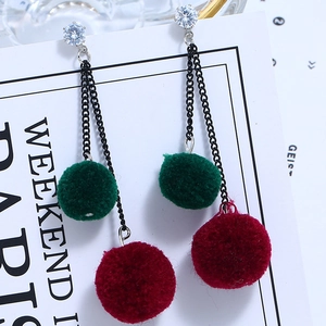 Detail of elegant long tassel earrings with dark green and burgundy faux fur pom poms