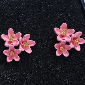 Details von rosa Blumenohrsteckern mit drei Blütenblättern und goldenen Details