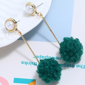 Detail view of long gold drop earrings with white pearls and dark green velvet pom-poms