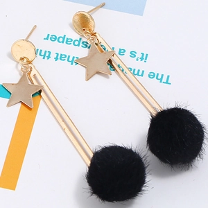 Detail of gold dangle earrings with metal star pendants and black plush pompom balls