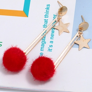 Detail of gold star earrings with red faux fur pompom charms and long elegant dangles