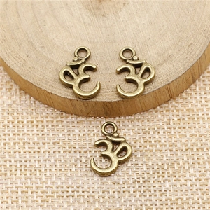 Drie antieke bronzen Om-symbool hangers op rustieke hout en linnen achtergrond