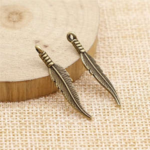 Pendentifs plumes vintage pour bijoux DIY sur fond de bois rustique et de lin