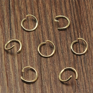 Set aus goldenen Eisen-Biegeringen für DIY-Schmuck auf dunklem Holzhintergrund