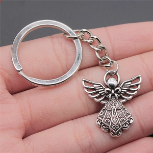Vintage silver angel wings keychain with bow and relief patterns held in hand