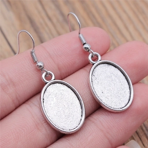 Silver oval cabochon earring settings for DIY jewelry making held in hand