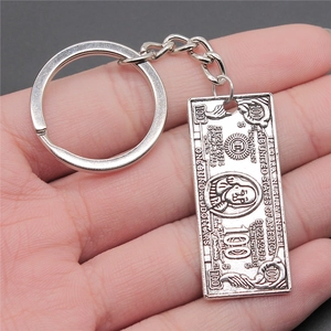Zinc alloy keychain with detailed 100 dollar bill pendant shown in hand for scale