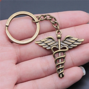 Vintage bronze Caduceus medical symbol keychain held in hand showing fine metal details