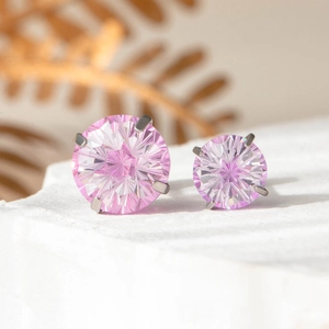 Boucles d'oreilles clous en zircon rose avec serti griffes sur fond de marbre