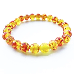 Dettaglio di perle in resina ambra da 8mm con motivi floreali rossi su bracciale yoga