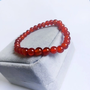 Elegant red agate beaded bracelet on velvet box, features smooth translucent gemstones