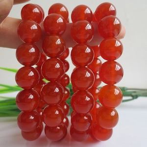 Vibrant red agate beaded bracelet with polished round gemstones shown in a hand