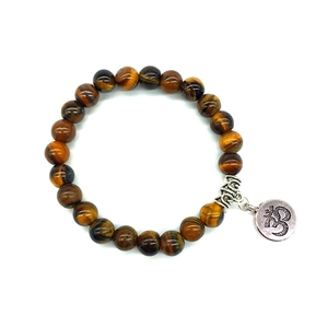Détail du bracelet en perles d'oeil de tigre avec pendentif Om argenté et pièces ciselées