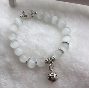 Pulsera de cuentas de ojo de gato con colgante de bola hueca sobre piel blanca