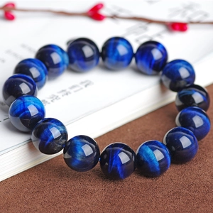 Makroansicht des blauen Tigerauge-Armbands mit Chatoyance-Effekt auf offenen Buchseiten