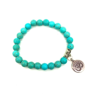 Vue détaillée des perles de turquoise bleu ciel et du pendentif Om en argent sur le bracelet
