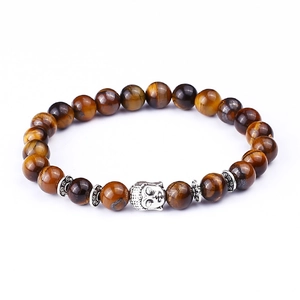 Macro detail of natural tiger eye beads and silver Buddha head on an elastic bracelet