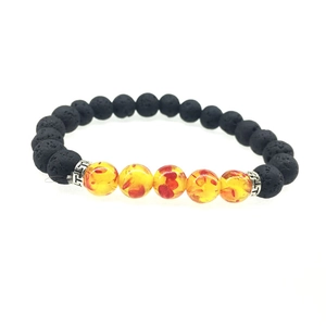 Dettaglio di bracciale in pietra vulcanica con perle di resina ambrata e distanziali