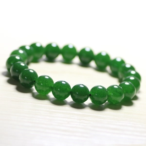 Macro shot of polished green chalcedony beads on a minimalist light wood background