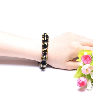 Dettaglio del bracciale con grani neri e mantra dorati indossato su un polso umano