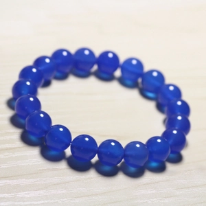 Deep blue chalcedony beaded bracelet with smooth translucent finish on wood background