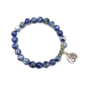 Détail de perles en marbre bleu et d'un charm avec symbole Om en argent sur un bracelet zen