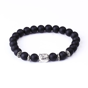 Macro shot of matte black lava stone beads with a silver Buddha head and spacer details
