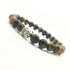 Macro shot of tiger eye beaded bracelet featuring a silver metal Buddha head charm