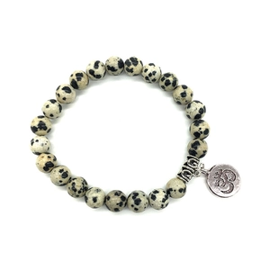 Détail macro des perles en jaspe dalmatien avec un pendentif Om argenté sur bracelet