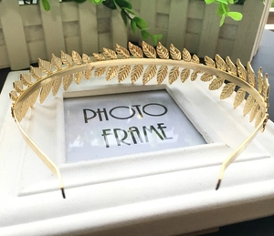 Detailed close-up of a golden leaf headband with Greek-style metallic foliage texture