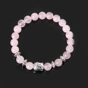 Detail of pink quartz bead bracelet with an ornate silver Buddha head and textured spacers