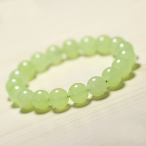 Polished light green chalcedony beaded bracelet on a minimalist wooden background