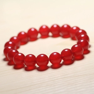 Macro shot of smooth red chalcedony bead bracelet on a light wood background