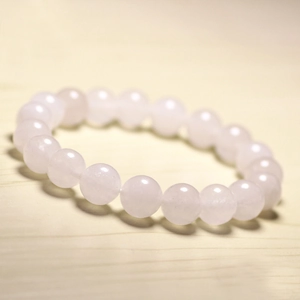 Close-up of pink quartz beaded bracelet with translucent stones on a light wood surface