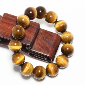 Macro shot of polished yellow tiger eye stone beads on a classic wood stand