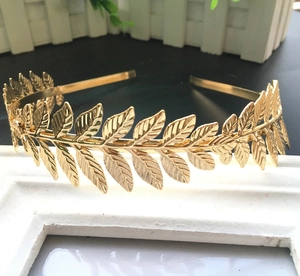 Detail of a golden laurel leaf headband displayed on a white photo frame