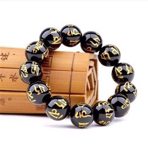 Bracciale in vetro di cristallo con perline mantra dorate su un tappeto di bambù