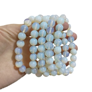 Gros plan d'un bracelet en opaline montrant des perles blanches et un reflet bleuté
