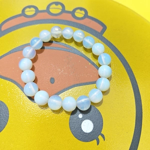 Détail du bracelet en perles d'opale montrant l'éclat blanc laiteux et reflet bleu