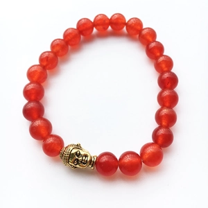 Gros plan de perles d'agate rouge avec breloque bouddha dorée sur bracelet élastique